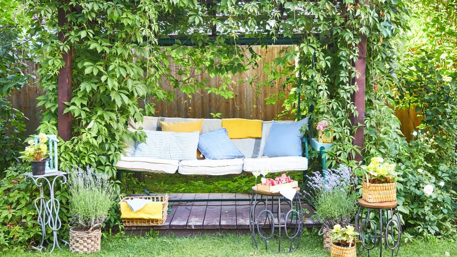 A beautiful garden swing with cushions and throw pillows surrounded by greenery.