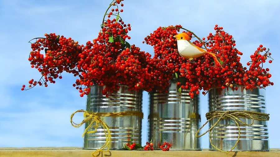 Tin cans filled with red berries and an artificial bird on it.