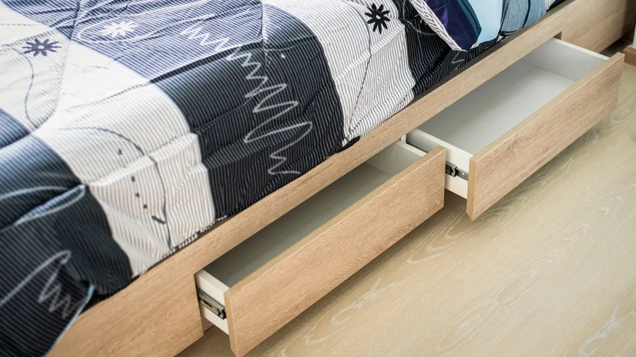 A wooden bed with built in drawers under it.