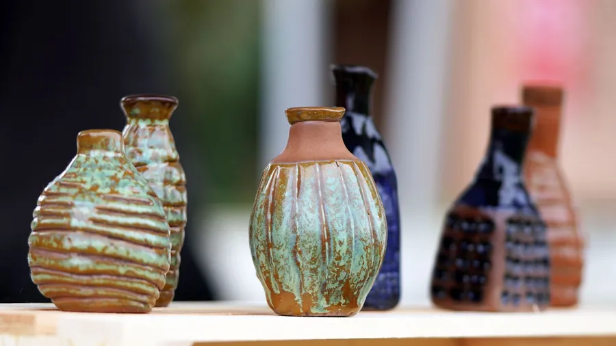 Beautiful handmade pottery pots in different colors placed on a wooden table/