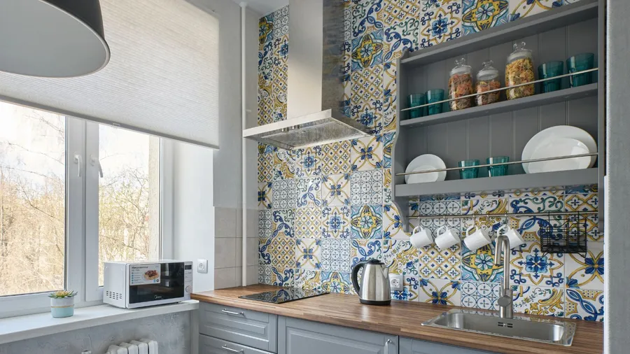 A cozy kitchen with colorful patterned tiles, open shelves displaying dishes and jars.
