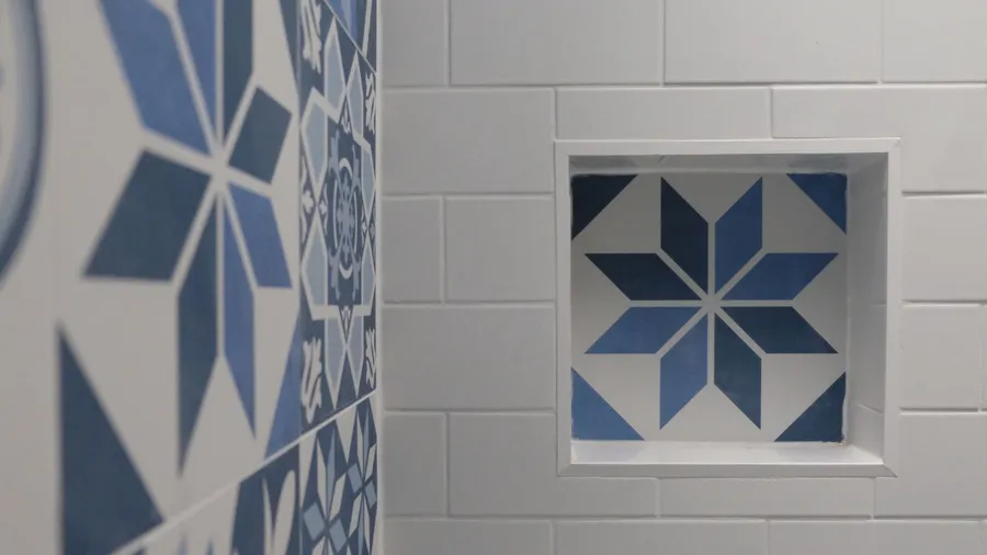 A shower niche on a white marble wall in a shower box.