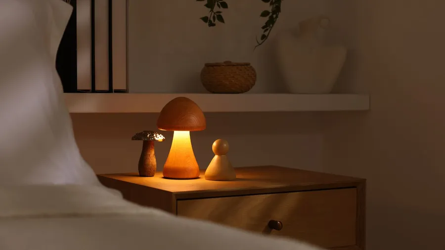 A soft bedside mushroom lamp on a wooden bedside table.