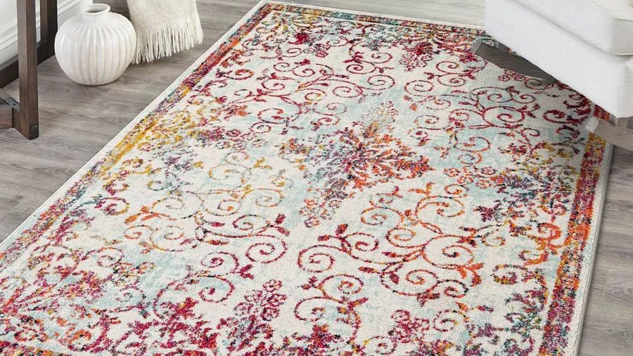 A handwoven area rug on a wooden floor in a living room.