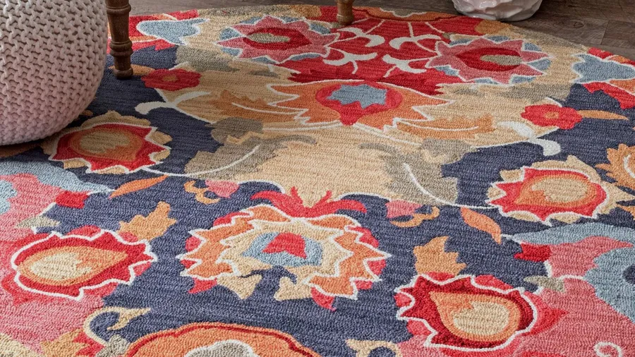 A hand tufted wool rug on a wooden floor.
