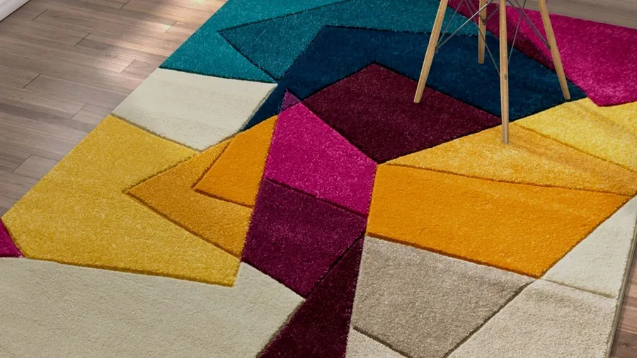 A vibrant color block rug with geometric patterns on a wooden floor.