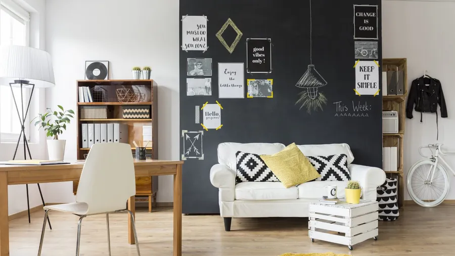 A living room interior with a black chalkboard wall with printed quotes and monochrome prints on it.