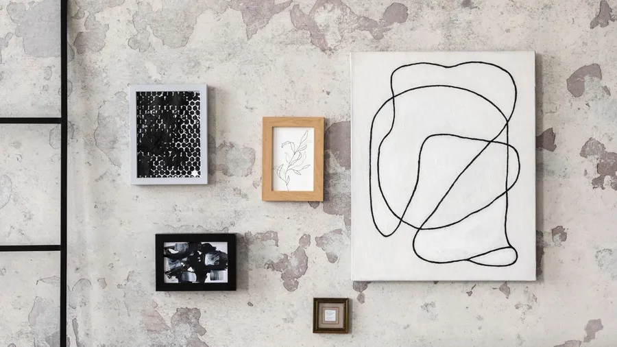 A gallery wall with minimalistic frames of different sizes with artwork hanging on it.