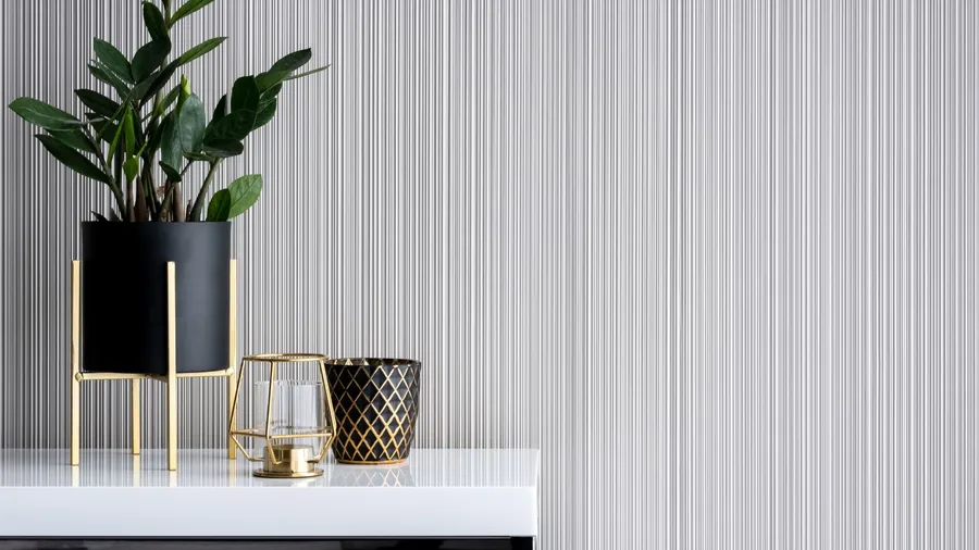 A plant pot and metallic decor accents on a white table in front of a fluted wall.