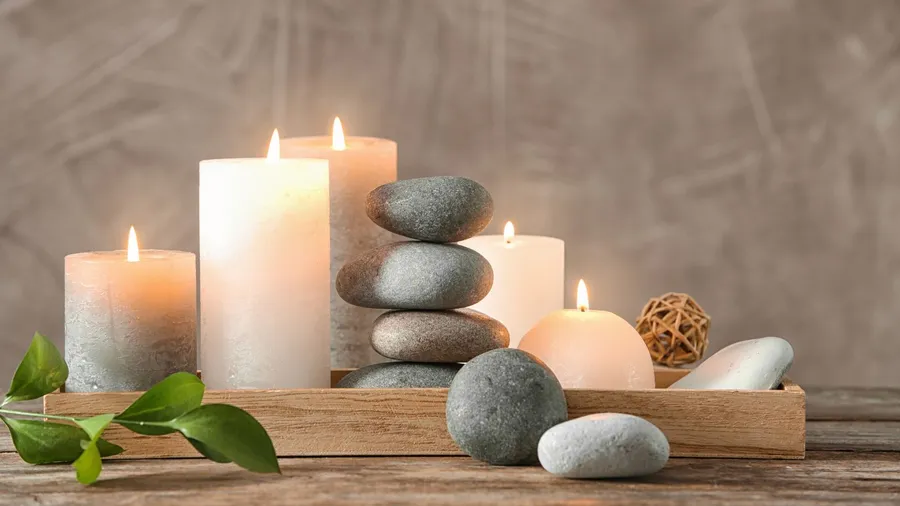 A wooden tray with candles and stones on a wooden surface.