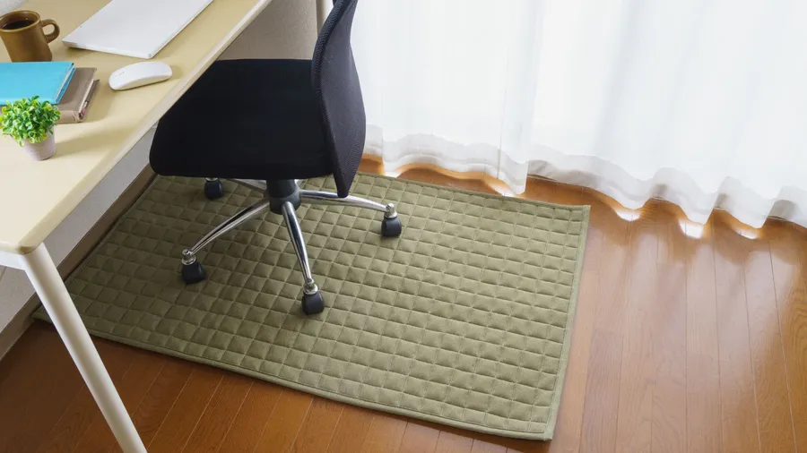 A cushion mat under the chair on a wooden floor in a home office.