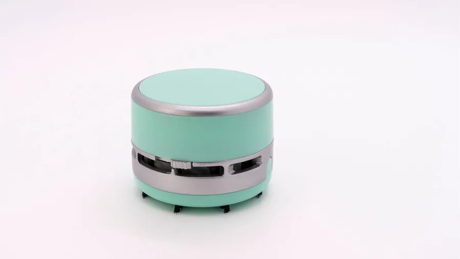 A mini desk vacuum on a white surface.