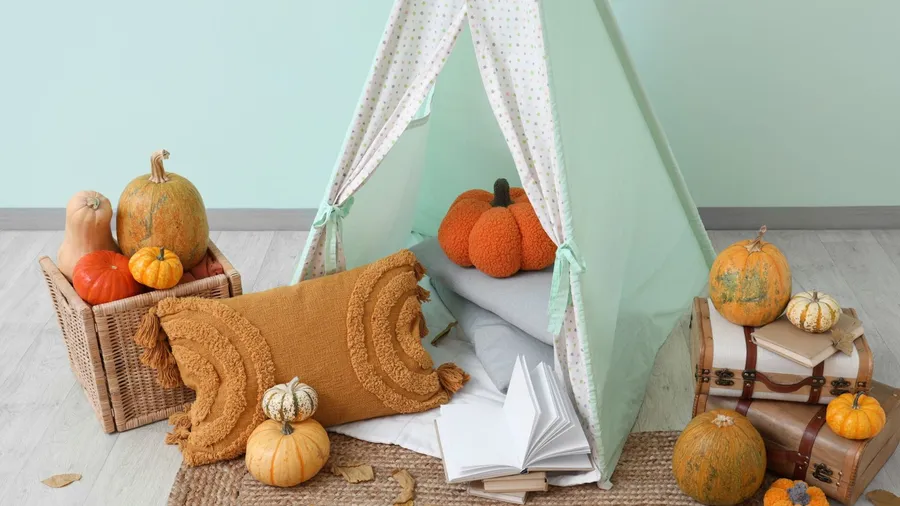 Interior of children's play room with tent, pumpkins, books, suit cases, leaves, and fall decor
