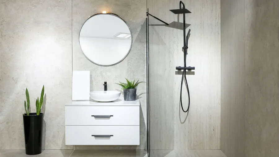 A bathroom interior with floating vanity, round metallic frame mirror, and rainfall showerhead.