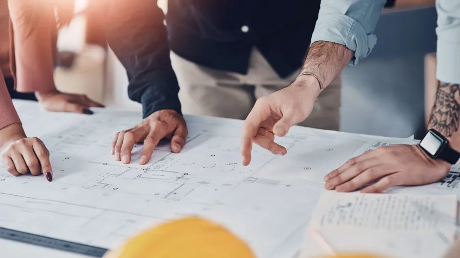 The image shows hands of three people planning ideas for the infrastructure project.