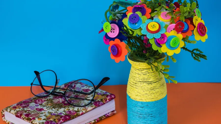 A DIY flower vase and a book on an orange table.