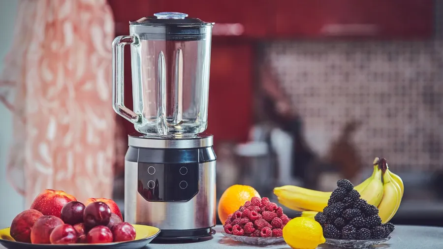 A high powered bender and different fruits placed on a table.