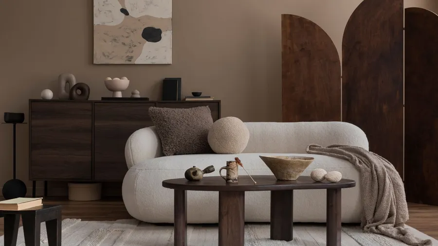 A stylish living room interior with wooden coffee table, wooden console, cozy white sofa, throw blanket, rug, and decor pieces.
