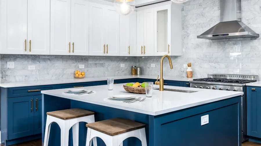 A bright kitchen with white and blue cabinetry and gold hardware.