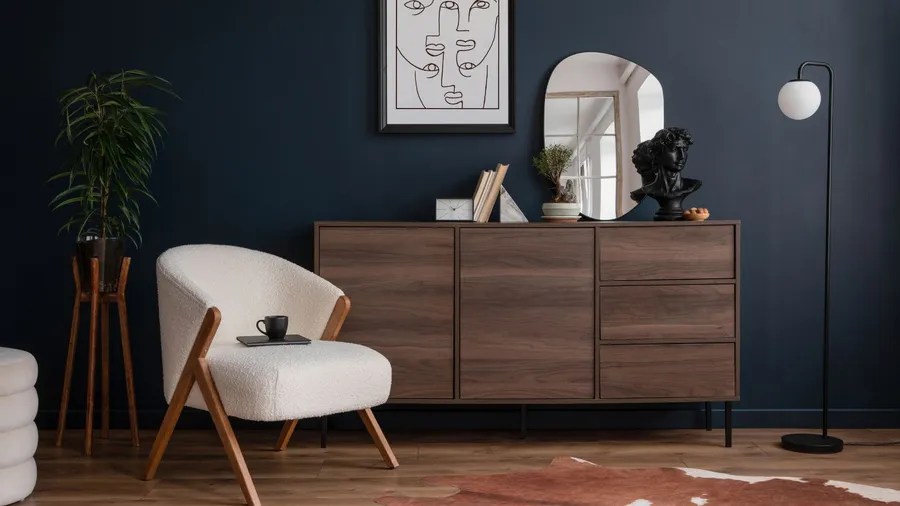 A stylish corner with a designer armchair, a wooden sideboard, and a decorative mirror.