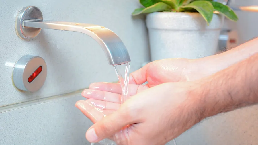 A man washing his hands from a smart faucet.