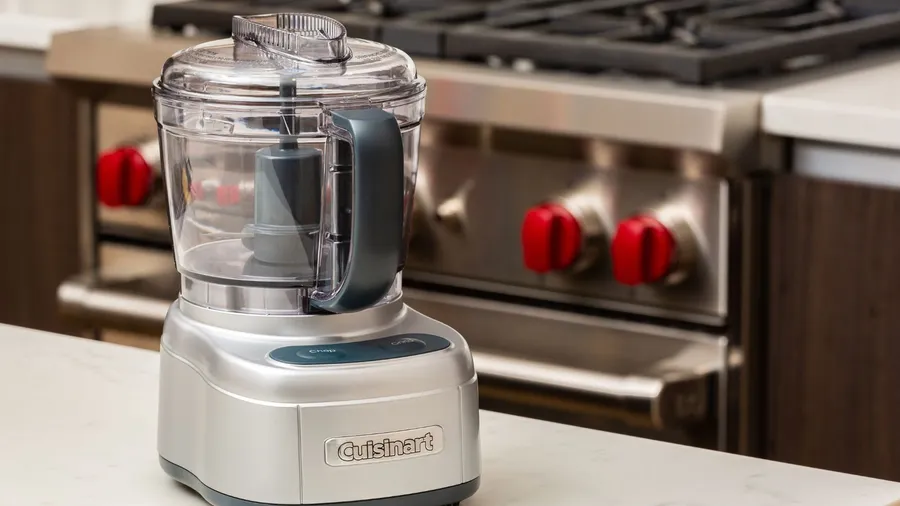 A food processor on a marble counter in a kitchen.