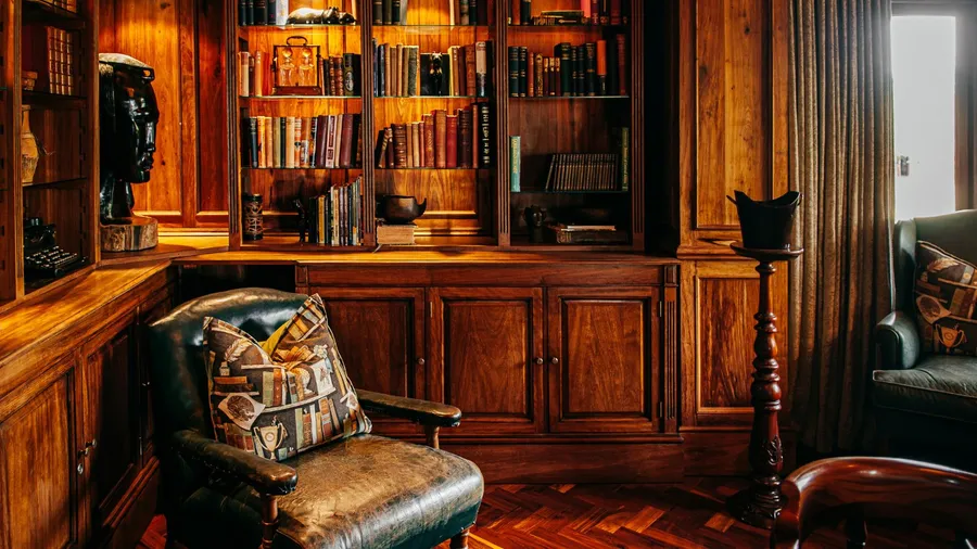 A cozy room interior with leather armchair, wooden bookshelf with collection of vintage books, decor accents, and sculpture.