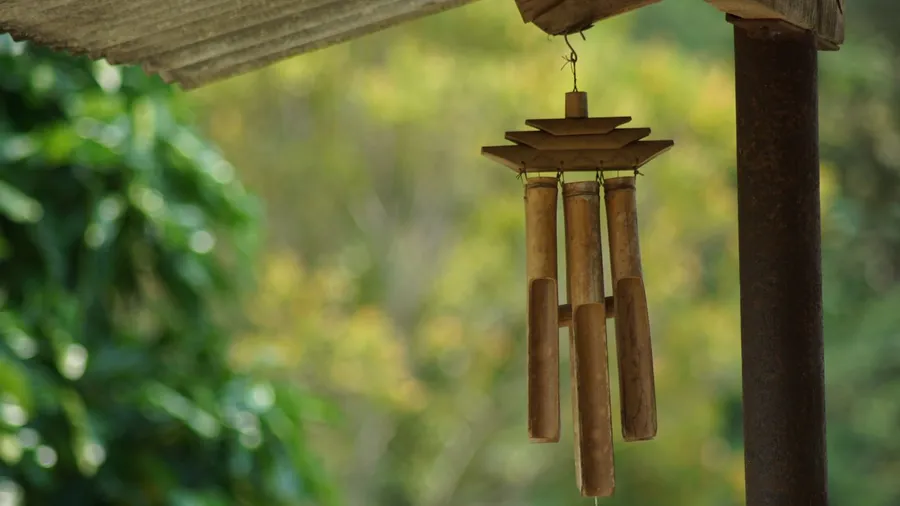 A bamboo wind chime hanging from the ceiling in a garden.