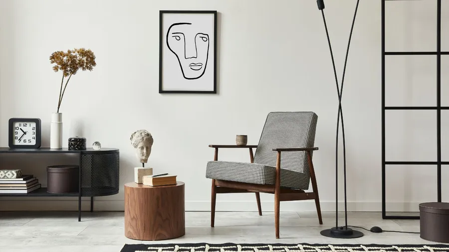 A stylish living room with a wooden armchair, wooden coffee table with book and sculpture, console table, rug, and framed artwork on the wall.