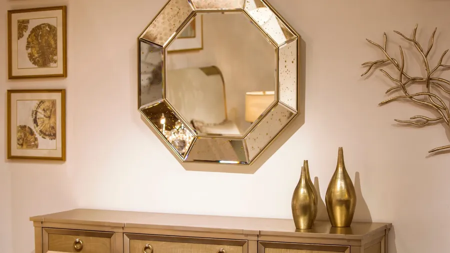 A living room interior with gold accent mirror and golden vases on console table.