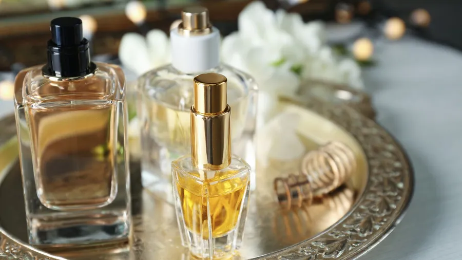 A golden decorative tray with perfumes on a white table.