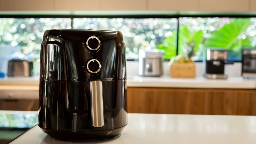 A black electric air fryer on a white counter.