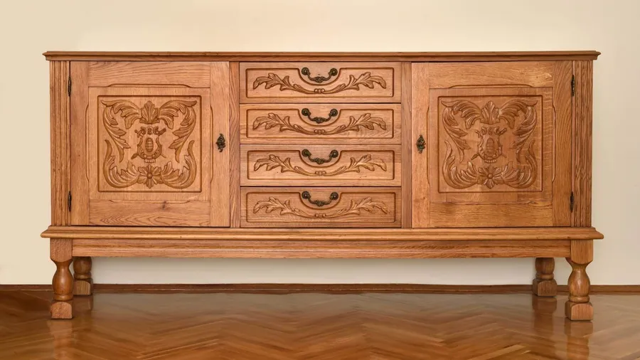 A vintage wooden dresser with decorative molding and brass hardware.