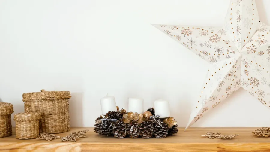 A beautifully arranged wooden shelf features woven baskets, pine cones, and a large star decoration.