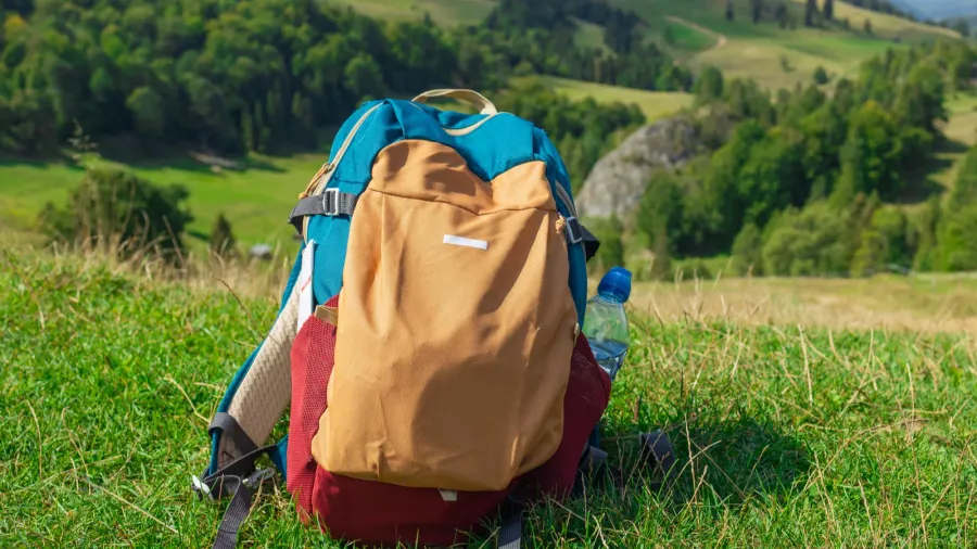 a colorful hiking backpack rests on a lush green hillside