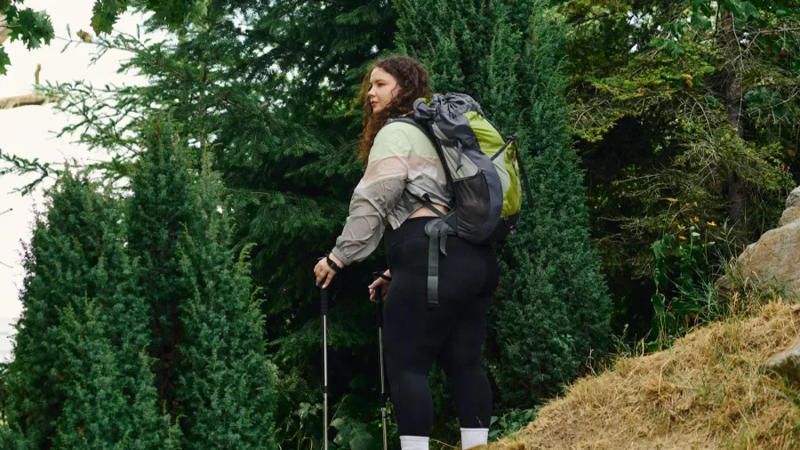 a confident plus size woman enjoys her hike amidst tall