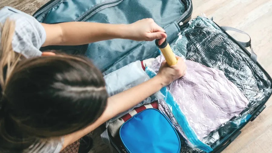 a girl packs things or clothes with a vacuum pump