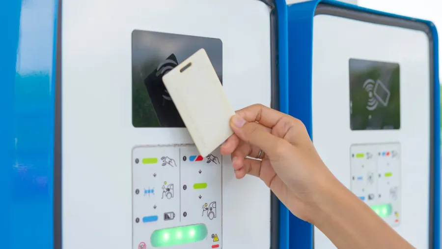 a hand tapping ev charging point card to reader machine