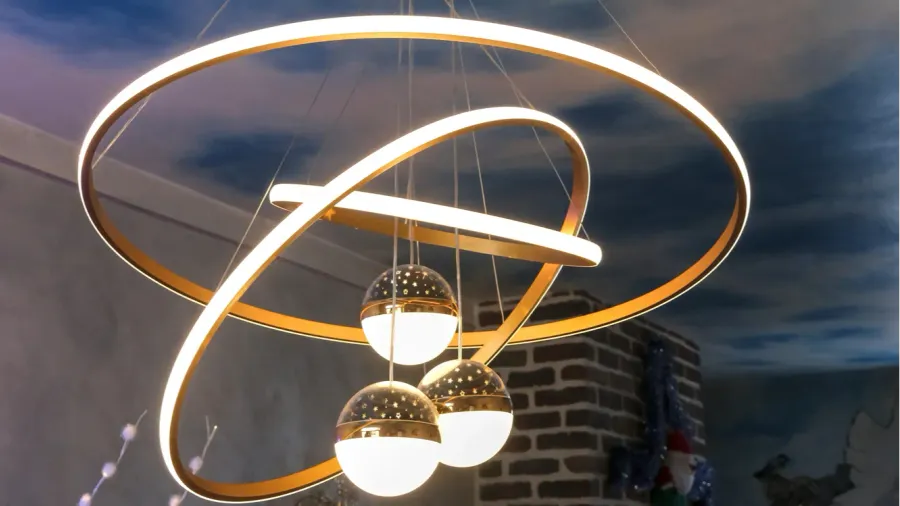 a modern chandelier with three glowing bulbs is suspended from