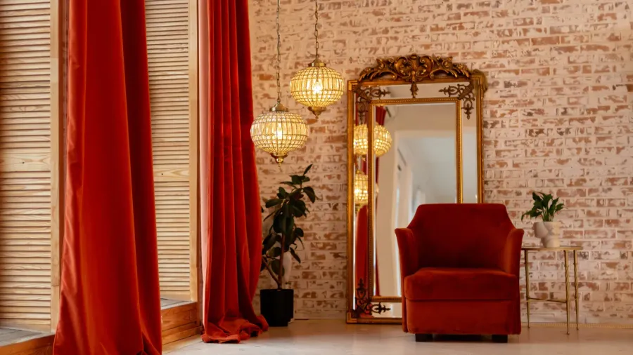 Cozy seating corner with red velvet armchair and ornate mirror.