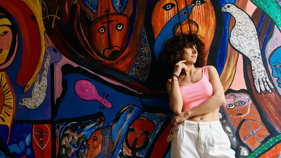 Woman standing infront of a vibrant, abstract art wall background.