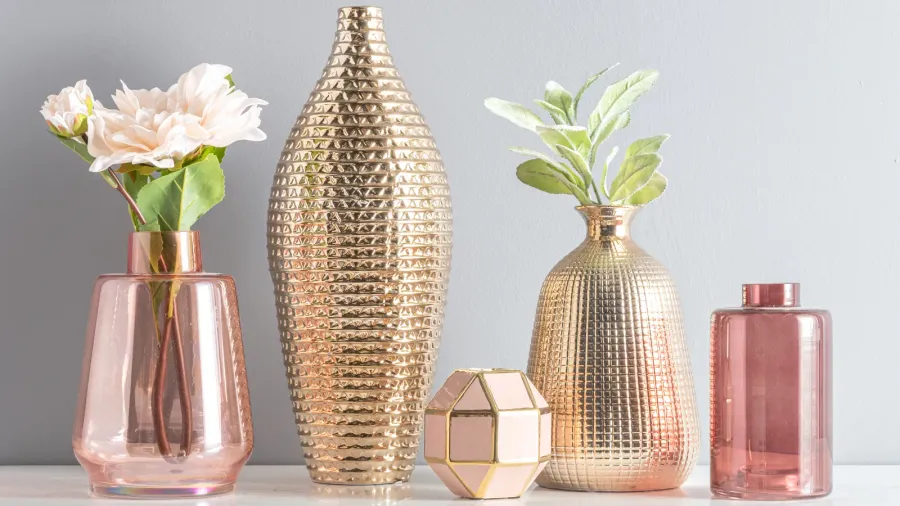 Assortment of gold and glass vases with unique shapes on a white table.