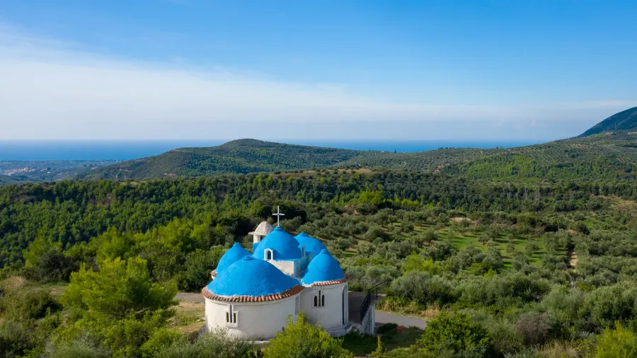 a white church with vivid blue domes stands nestled among