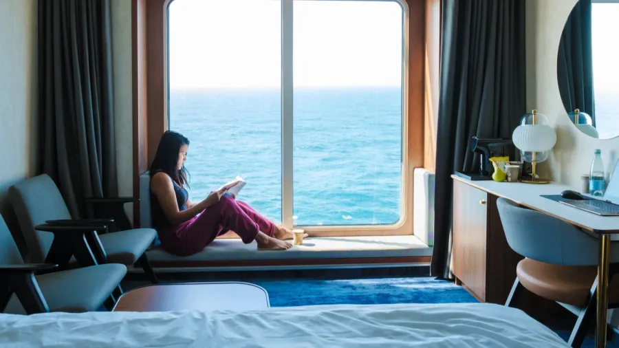 a woman relaxes by a large window in a cruise