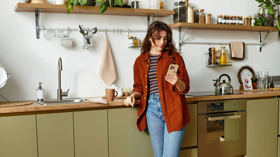 a young woman stands in a warm kitchen contemplating her