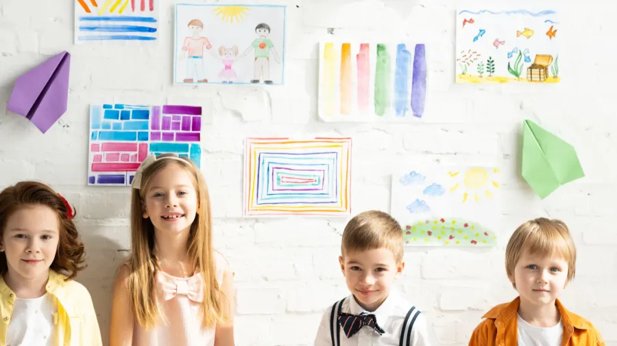 adorable kids posing and looking at camera near colorful paintings