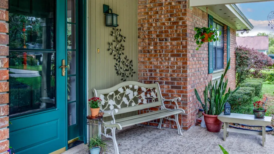 american house front porch decorated with plants and bench stone