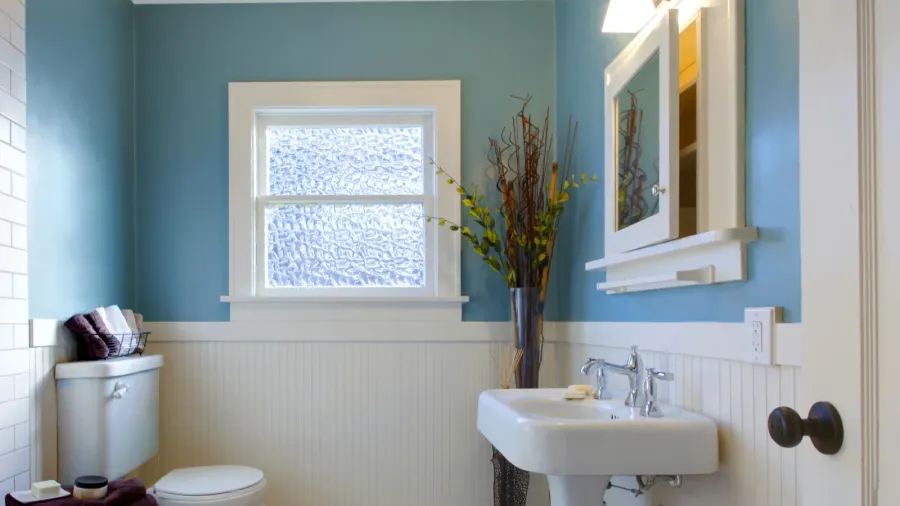A bathroom interior with blue walls, sink, and a mirrored medicine cabinet.