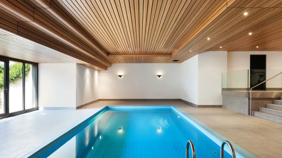 Indoor swimming pool with bright lighting and tiled floor.