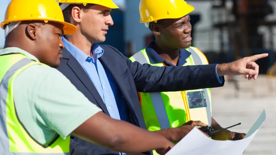 Three construction workers analyzing project details.